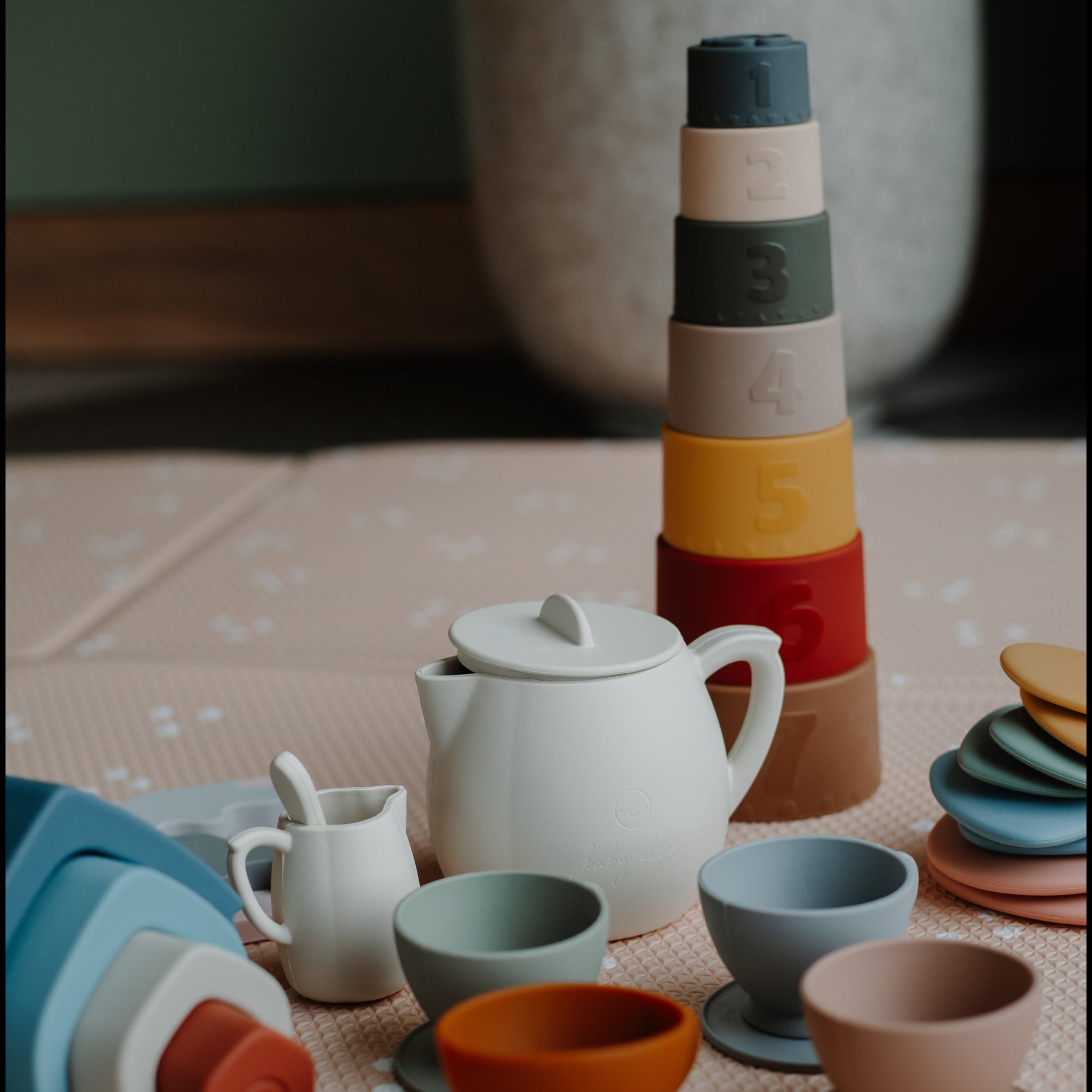 Baby playing with silicone stacking cups in neutral nursery